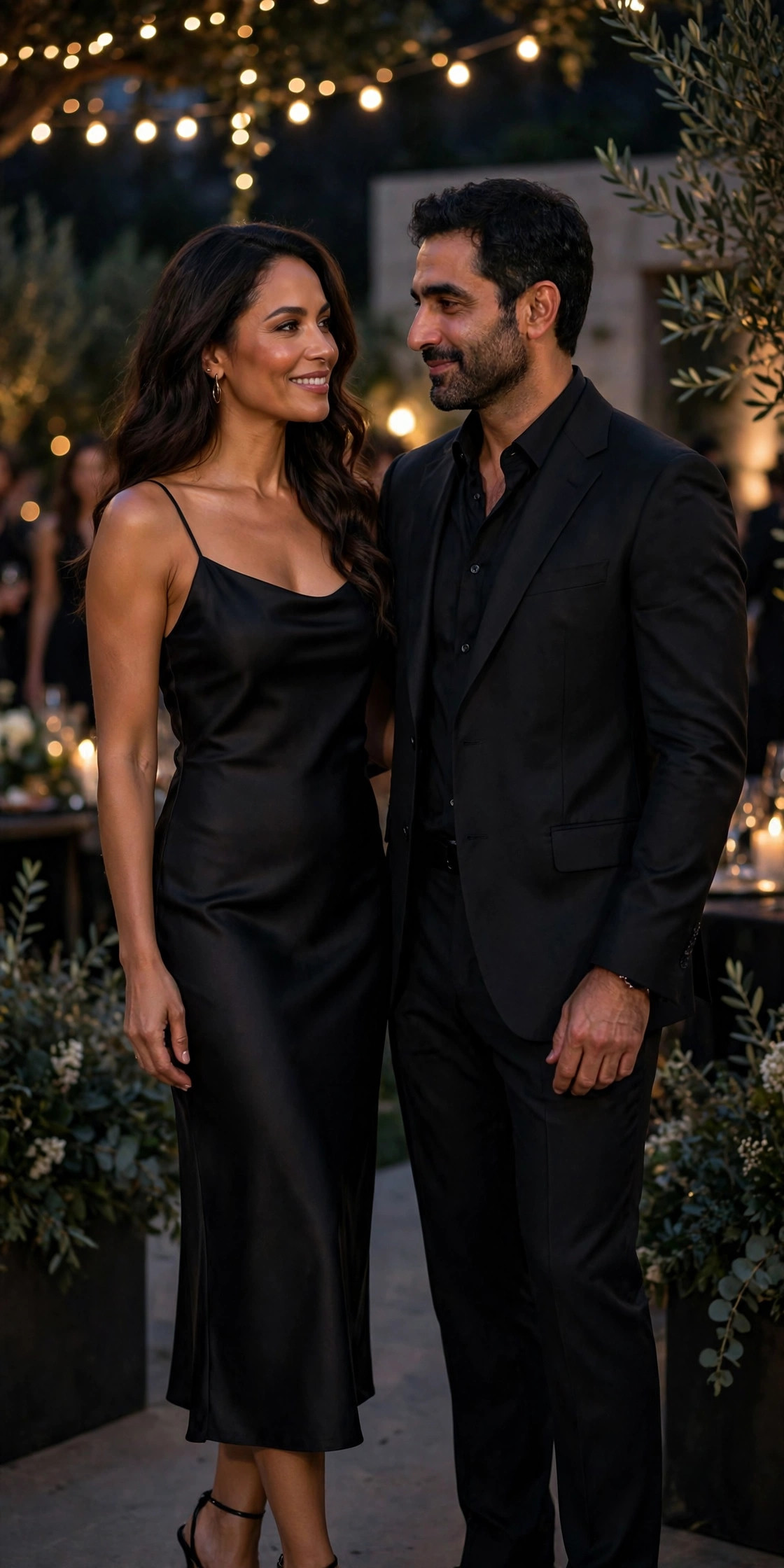 Elegant couple at an evening event, woman in black satin slip midi dress and man in tailored black suit, formal matching couple outfit