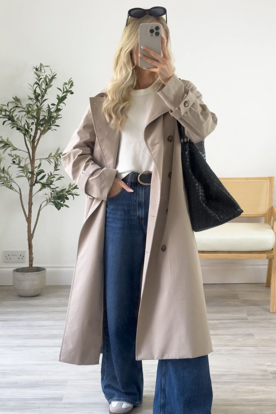 Beige trench coat worn open over a white top and wide-leg jeans